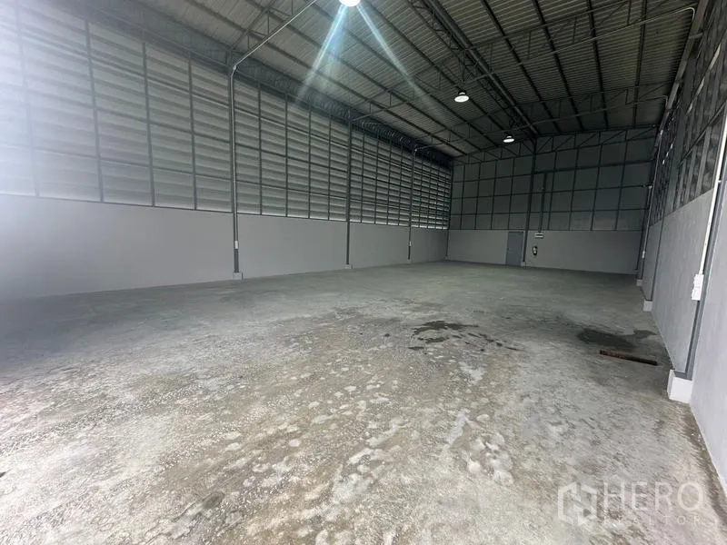 货栈 出租在Prawet, Bangkok - 高挑仓库内部，钢结构屋顶、通风百叶金属墙与混凝土地面，位于曼谷Prawet。