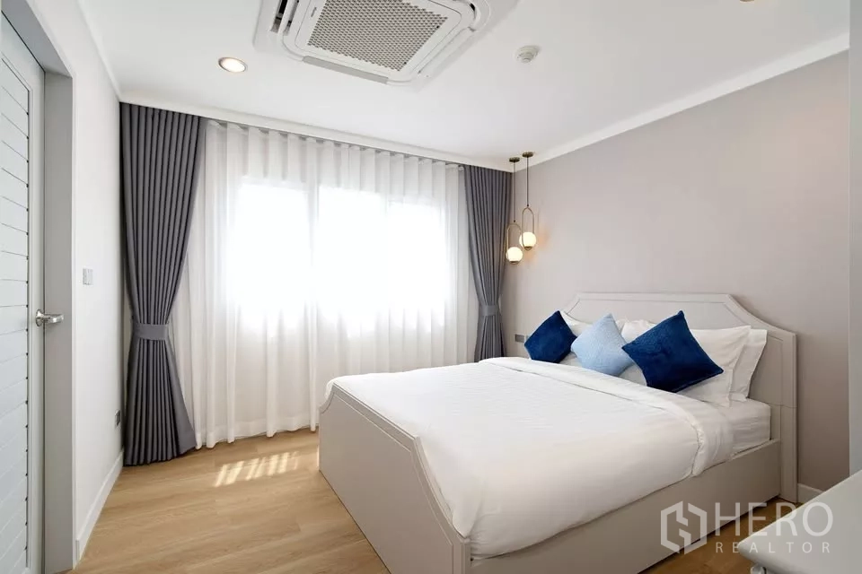 คอนโด ขายในBang Na, Bangkok - ห้องนอนบรรยากาศสงบ เตียงขาว ผ้าม่านสองชั้น แอร์แขวนฝ้า และโคมแขวน