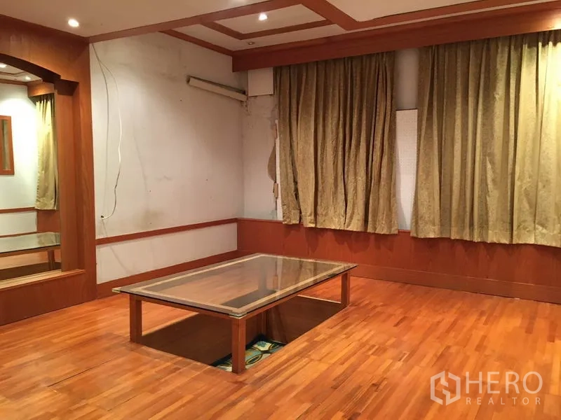 零售空间 出租在Watthana, Bangkok - 木地板房间，嵌入式筒灯，窗帘与低矮玻璃桌。