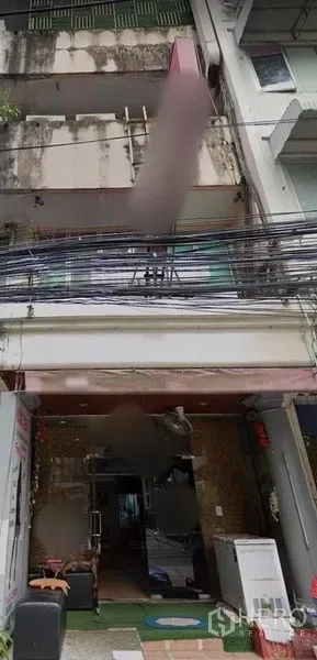 Shophouse for rent in Watthana, Bangkok - Four-storey shophouse facade with balconies, an open ground-floor shopfront and overhead power lines in the Phrom Phong area of Watthana, Bangkok.