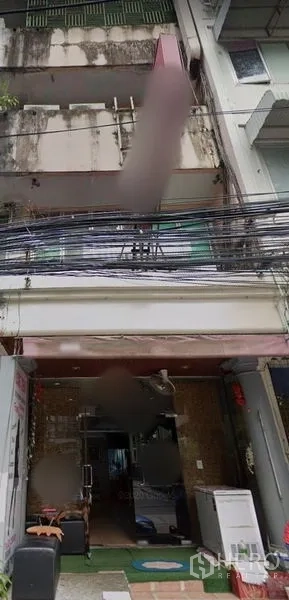 Shophouse for rent in Watthana, Bangkok - Four-storey shophouse facade with balconies, an open ground-floor shopfront and overhead power lines in the Phrom Phong area of Watthana, Bangkok.