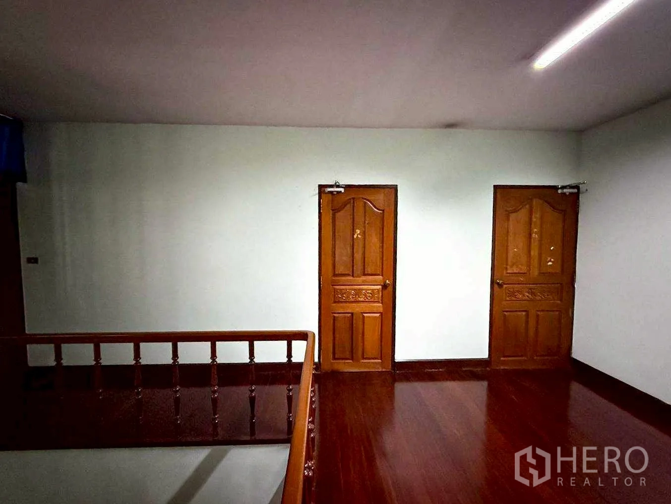 Home Office for rent in Bang Rak, Bangkok - Upper landing with two wooden doors and staircase railing.