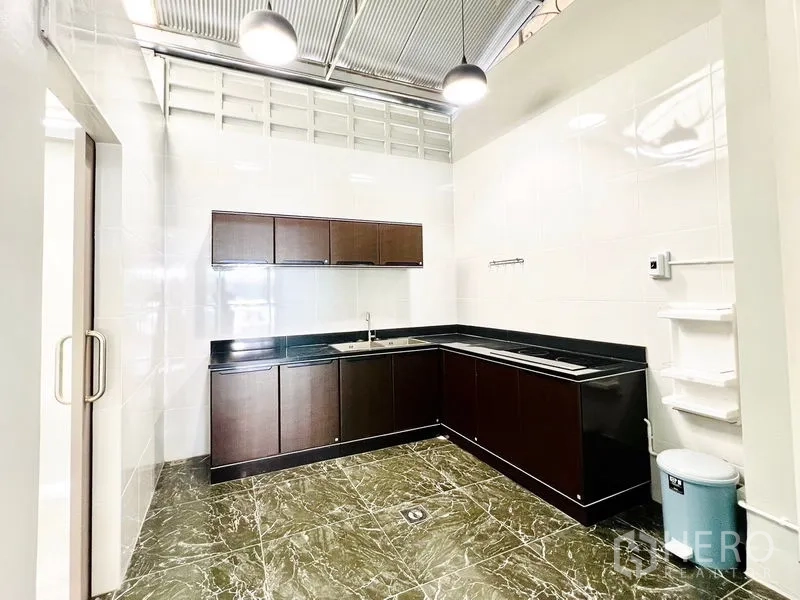 联排别墅 出租在Prawet, Bangkok - 宽敞泰式厨房，深色橱柜、仿石地面与高挑吊灯