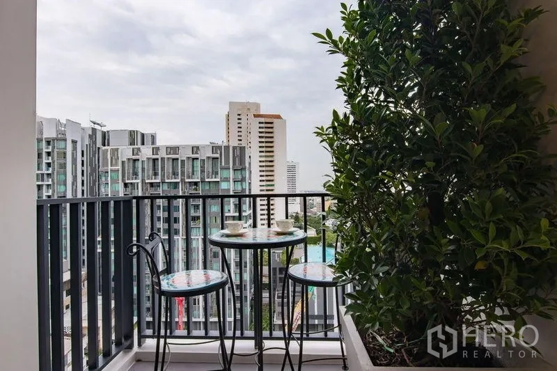 公寓 出售在Watthana, Bangkok - 私享阳台，摆放小圆桌与绿植，远眺城市天际线。