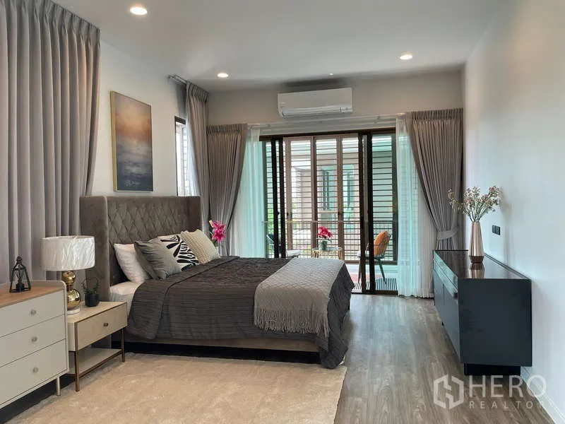 Detached House for rent in Bang Kapi, Bangkok - Spacious master bedroom with balcony access and upholstered headboard.
