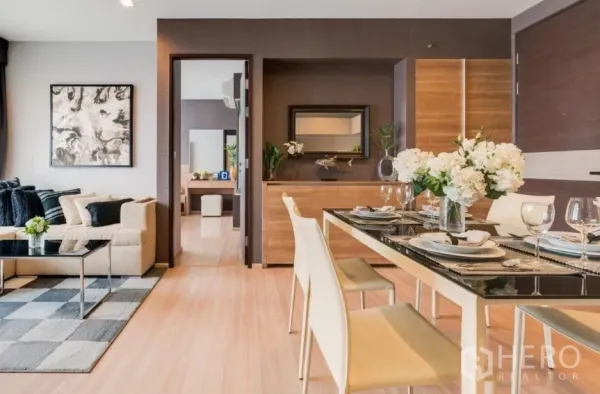Condominium for rent in Sathon, Bangkok - Open-plan dining and living area with wood flooring, modern table setting and neutral decor.