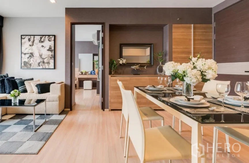 Condominium for rent in Sathon, Bangkok - Open-plan dining and living area with wood flooring, modern table setting and neutral decor.