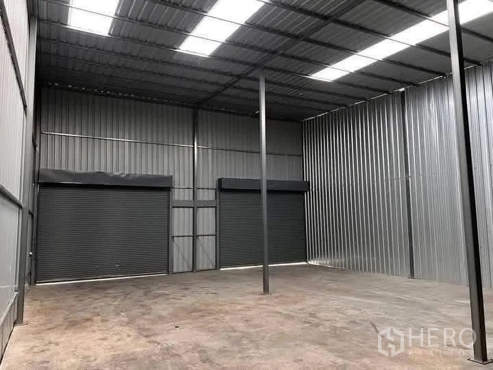 Warehouse for rent in Lat Krabang, Bangkok - Spacious interior with a high roof, skylight panels, and two roller shutters.