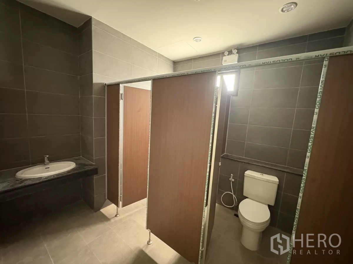 工厂 出租在Bang Pakong, Chachoengsao - 员工卫生间，灰色瓷砖，独立隔间带马桶和洗手盆。