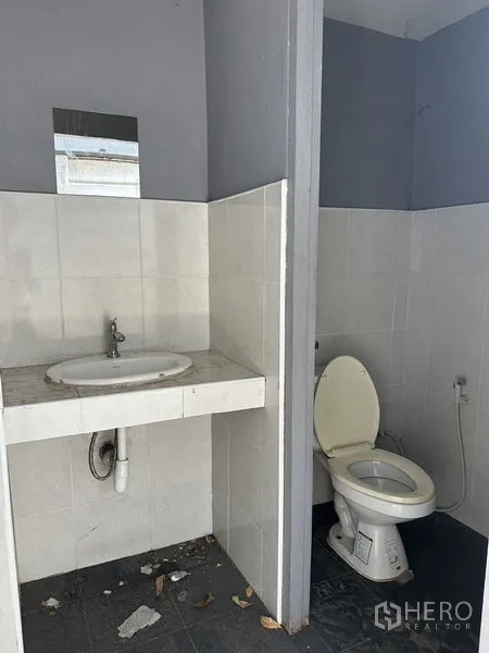 คลังสินค้า ให้เช่าในLat Phrao, Bangkok - ห้องน้ำแบบเรียบง่าย มีโถสุขภัณฑ์ สายฉีดชำระ และอ่างล้างมือผนังกระเบื้อง