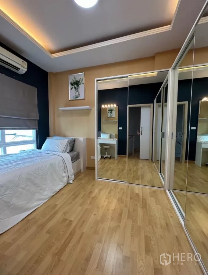 Townhouse for rent in Wang Thonglang, Bangkok - Bedroom with full-height mirrored wardrobes and wood floors