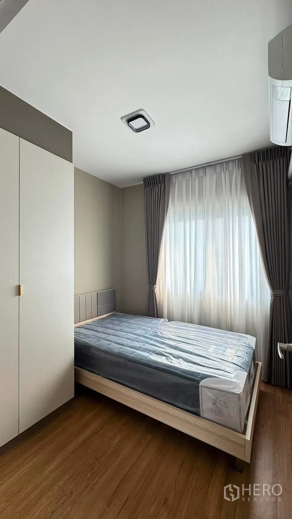 Townhouse for rent in Bang Phli, Samut Prakan - Cozy bedroom with bed, full-length curtains and a wall-mounted air conditioner.