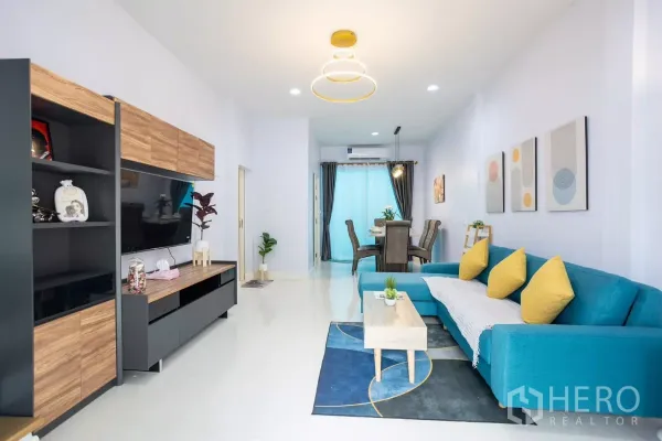 ทาวน์เฮาส์ ให้เช่า - ห้องนั่งเล่นสว่าง โซฟา L สีฟ้า โต๊ะกลาง และชั้นวางทีวีลายไม้