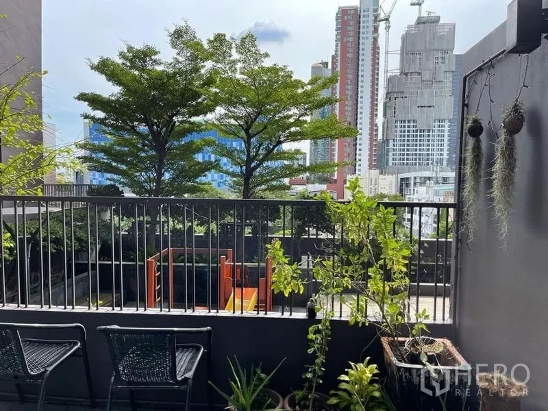 Condominium for sale in Watthana, Bangkok - Balcony with potted plants facing city skyline and treetops near Ekkamai.