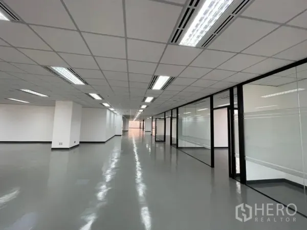 办公空间 出租在Din Daeng, Bangkok - 长形办公走道，玻璃隔断会议室与明亮吊顶灯。