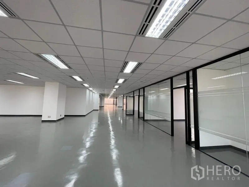 办公空间 出租在Din Daeng, Bangkok - 长形办公走道，玻璃隔断会议室与明亮吊顶灯。