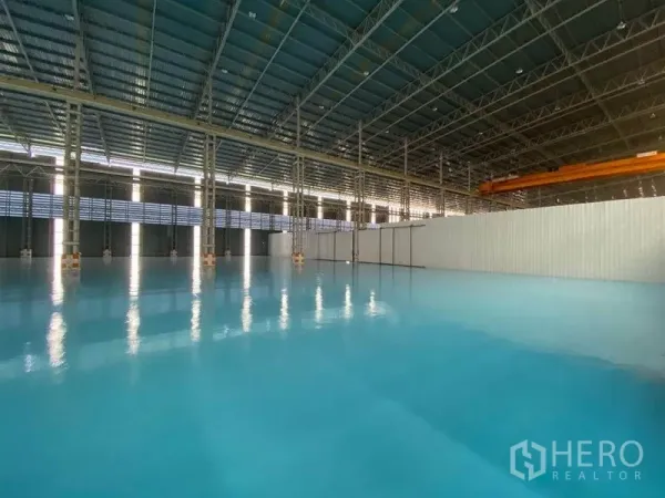 Factory for rent in Khlong Toei, Bangkok - Large warehouse bay featuring glossy blue epoxy-coated flooring and ventilated wall panels.