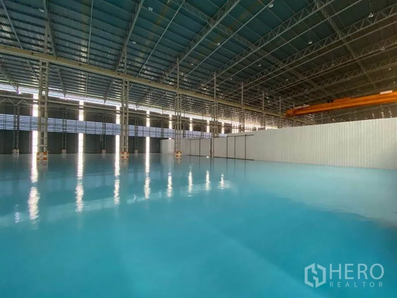 Factory for rent in Khlong Toei, Bangkok - Large warehouse bay featuring glossy blue epoxy-coated flooring and ventilated wall panels.
