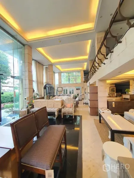 零售空间 出租在Wang Thonglang, Bangkok - 挑高零售展厅，暖色氛围灯、玻璃入口、石柱与面向绿景的大窗。
