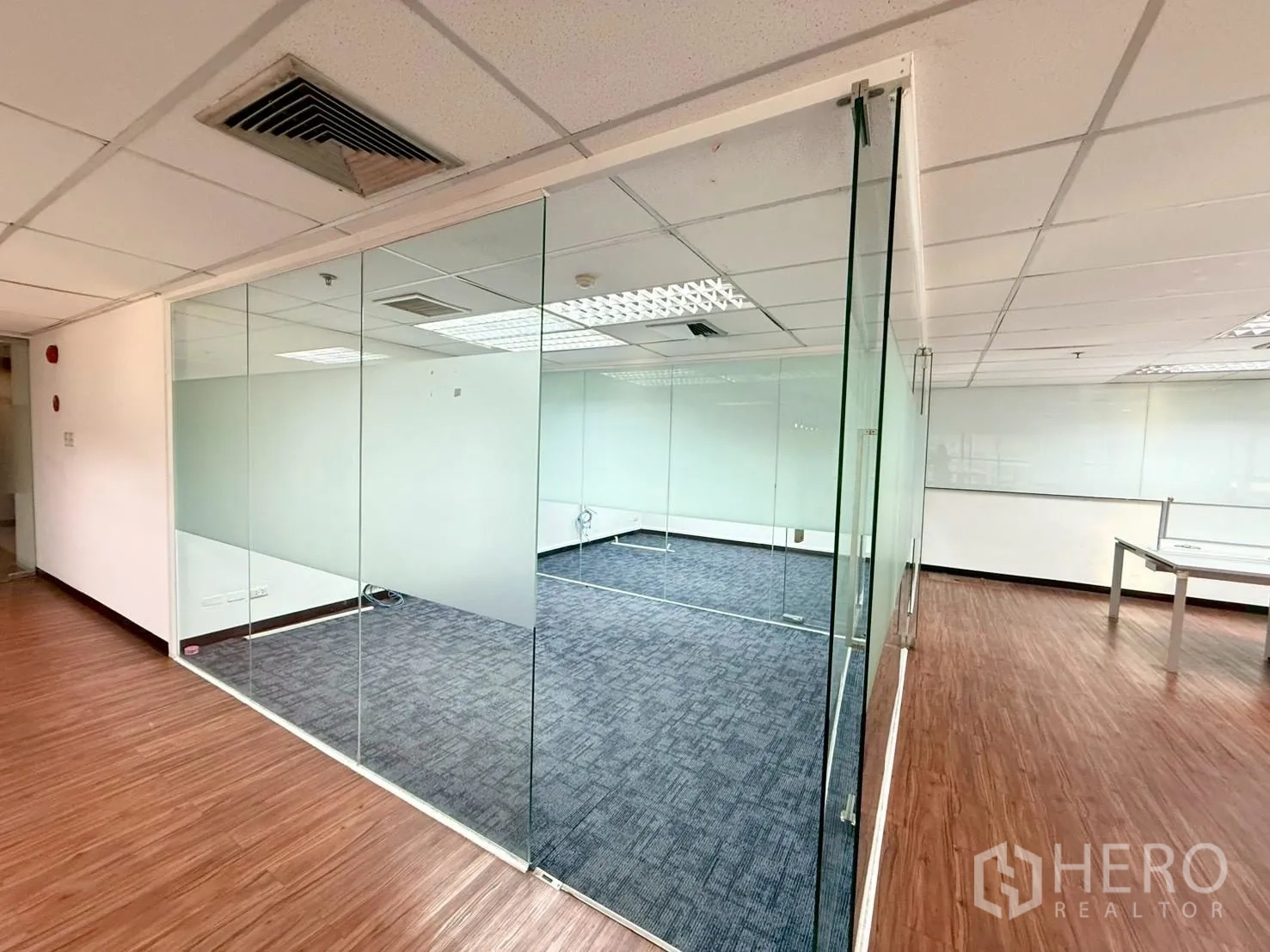 ออฟฟิศ for rent in Watthana, Bangkok - ห้องประชุมมุมออฟฟิศกั้นกระจกใส ปูพรมภายในและพื้นลายไม้นอกห้อง.