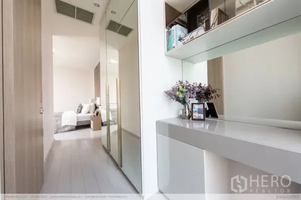 Condominium for rent in Pathum Wan, Bangkok - Corridor with mirrored wardrobe and study console leading to a modern bedroom.