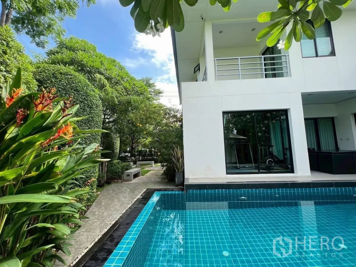 Detached House for rent or sale in Prawet, Bangkok - Poolside walkway bordered by lush hedges and tropical plants.