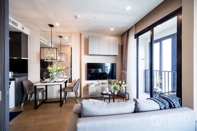 Condominium for rent in Watthana, Bangkok - View from sofa to dining table and kitchen with mirrored wall and balcony doors.