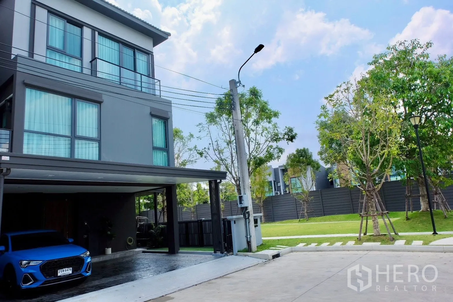 Semi-detached House for sale in Prawet, Bangkok - Side view of the house beside a landscaped park and streetlight.