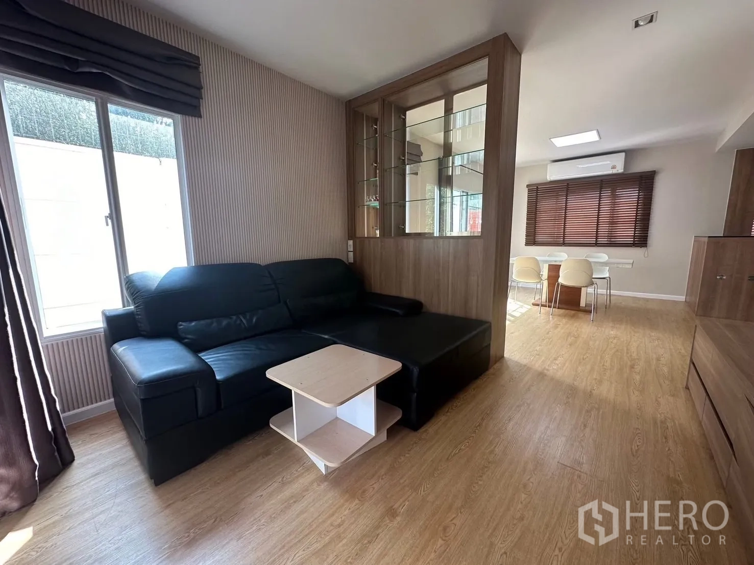 บ้าน ให้เช่า - ห้องนั่งเล่นสว่าง โซฟาหนังสีดำ และตู้โชว์กระจกกั้น