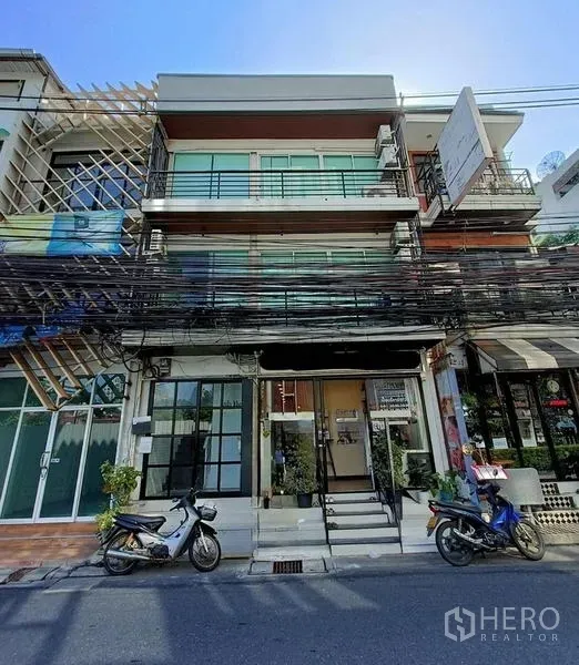 店屋 出售在Bang Rak, Bangkok - 三层商铺外立面，整面玻璃与阳台，街边停有摩托车