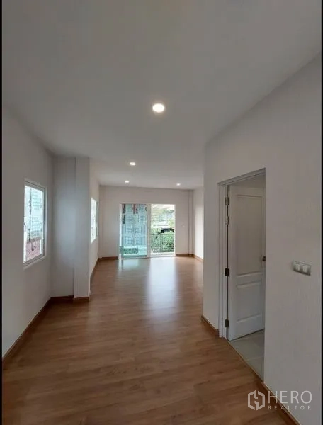 บ้าน ขายในBang Yai, Nonthaburi - โถงพักผ่อนพื้นไม้ ไฟดาวน์ไลท์ และประตูกระจกบานเลื่อนออกสู่พื้นที่ภายนอก