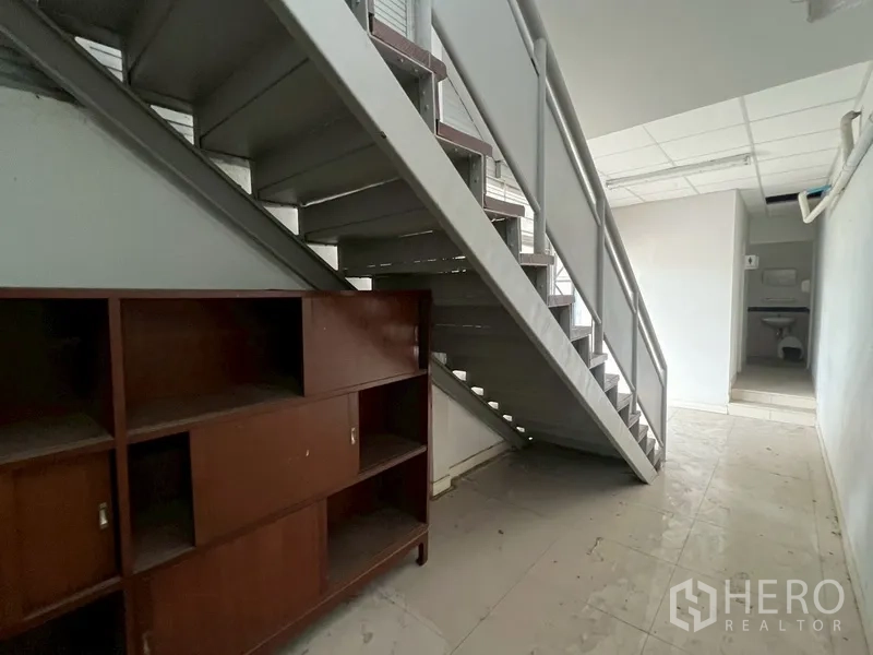 店屋 出租在Phra Khanong, Bangkok - 楼梯下储物区，带木柜，可见后方卫生间。