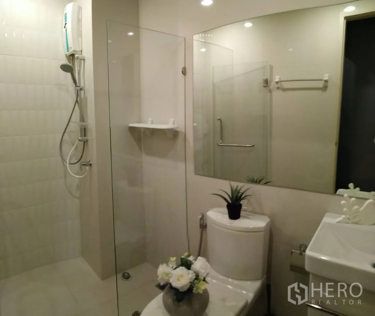 Condominium for rent in Huai Khwang, Bangkok - Clean bathroom with glass shower enclosure, large mirror and water heater