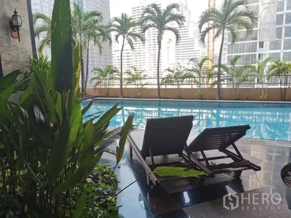 Condominium for rent in Watthana, Bangkok - Pool deck with sun loungers and tropical greenery overlooking the Bangkok skyline.