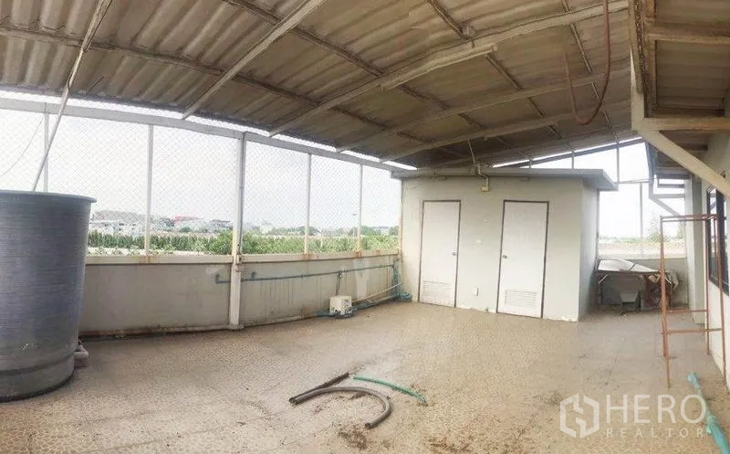 Office Space for rent or sale in Don Mueang, Bangkok - Covered rooftop terrace with utility area, water tank and open city views behind mesh fencing.