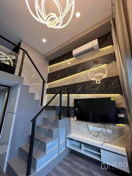 คอนโด ขายในChatuchak, Bangkok - ห้องนั่งเล่นโมเดิร์น บันไดราวกระจก ผนังหินอ่อนพร้อมไฟซ่อน ทีวีติดผนัง และเครื่องปรับอากาศ