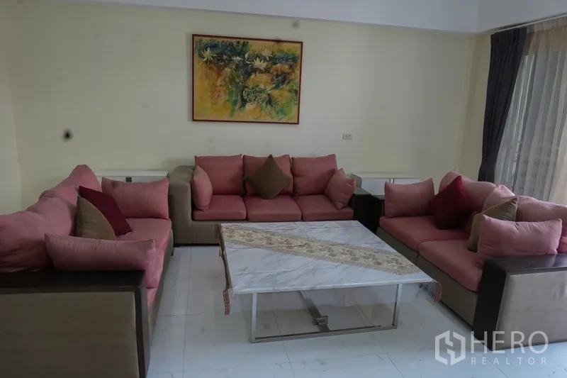 สำนักงานที่บ้าน ให้เช่า - มุมรับแขกอบอุ่น โซฟาสีชมพูล้อมโต๊ะกลางท็อปหินอ่อน และภาพติดผนัง