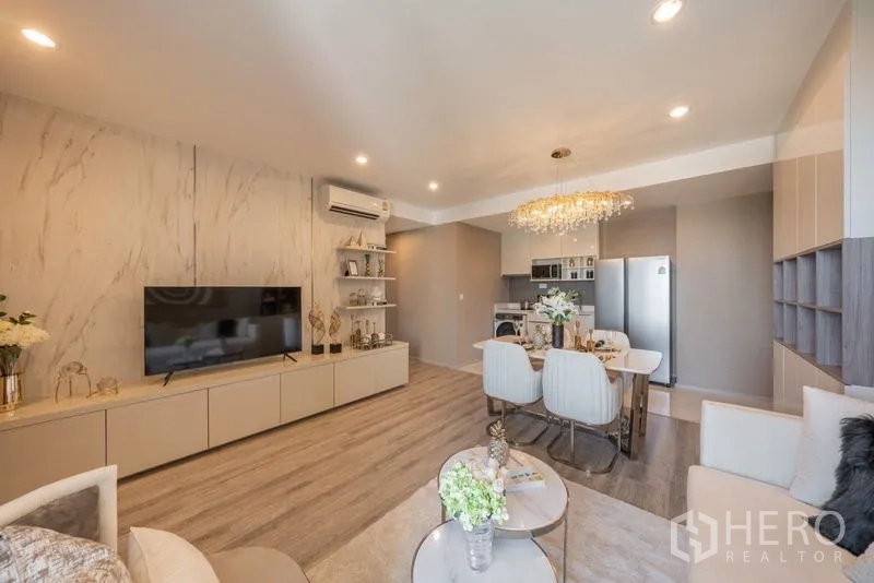 Condominium for rent in Bang Na, Bangkok - Spacious living room with long TV console, wood flooring and dining area leading to the kitchen.