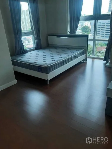 Condominium for rent or sale in Huai Khwang, Bangkok - Sunlit bedroom featuring corner windows and city skyline outlook
