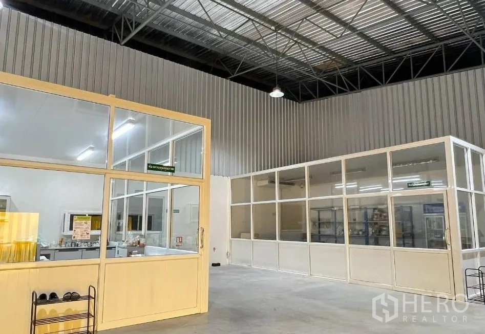 Factory for rent or sale in Sai Noi, Nonthaburi - Factory interior with high metal roof, glass-partitioned clean rooms and offices, and a concrete floor with bright lighting.