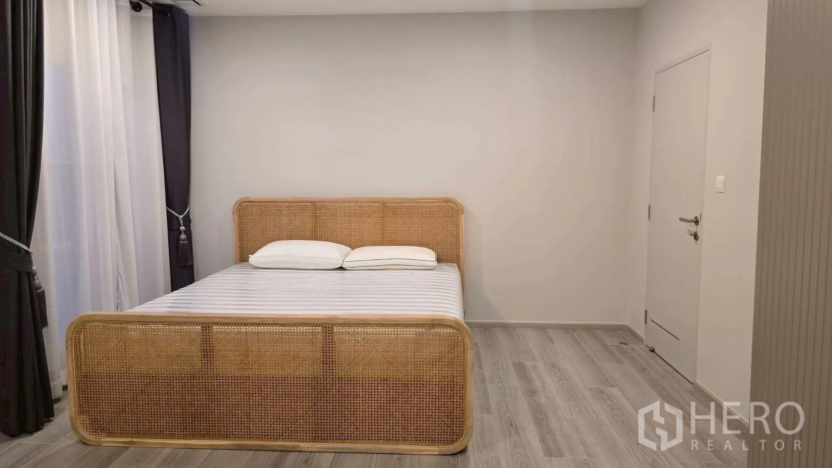 Semi-detached House for rent in Prawet, Bangkok - Minimal bedroom with rattan bed frame, curtains and wood-look flooring.