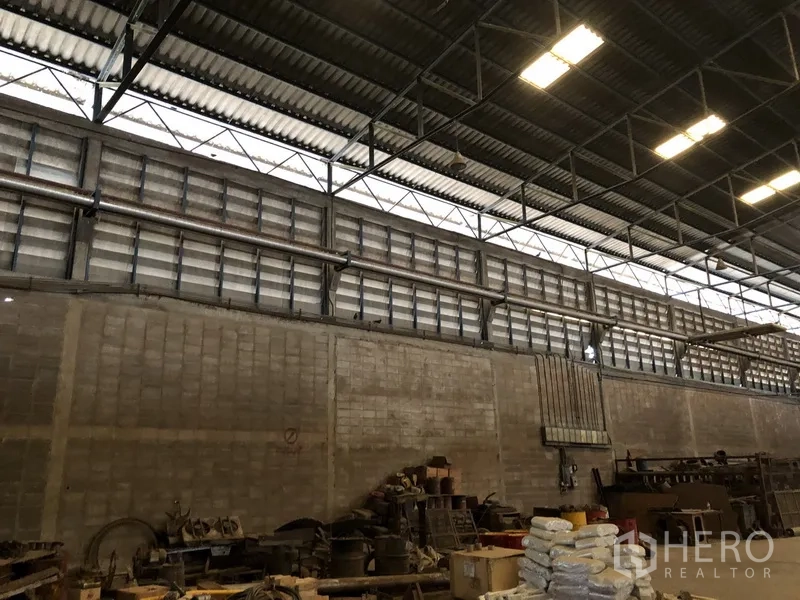 工厂 出租在Bang Bua Thong, Nonthaburi - 厂内通风砖墙与高位百叶窗，上方管线可见