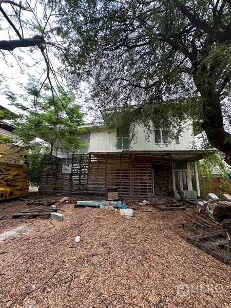 Detached House for rent in Watthana, Bangkok - Front of a two-storey white house with a large tree and cluttered yard.