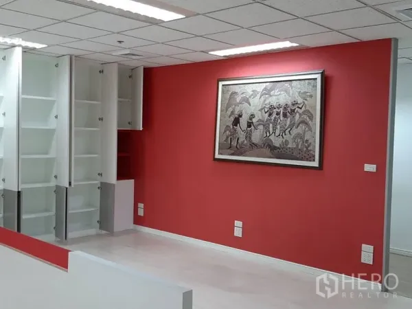 办公空间 出租在Bang Rak, Bangkok - 成品办公室一隅，红色主题墙、挂画与开放式白色储物柜。