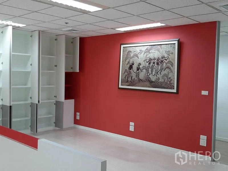 办公空间 出租在Bang Rak, Bangkok - 成品办公室一隅，红色主题墙、挂画与开放式白色储物柜。