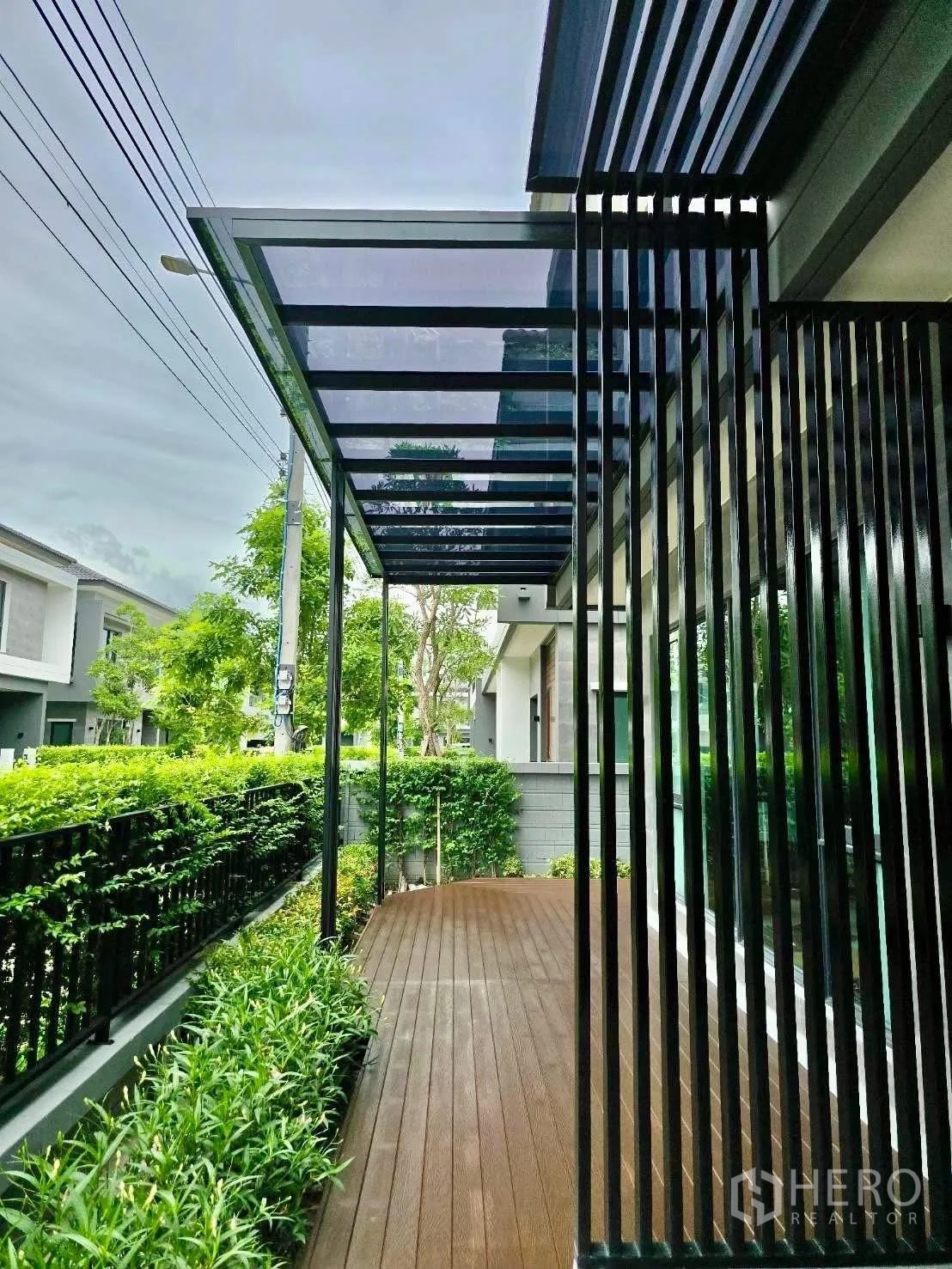 独栋房屋 for rent in Bang Phli, Samut Prakan - 户外覆顶木地台，旁有绿篱与黑色格栅。