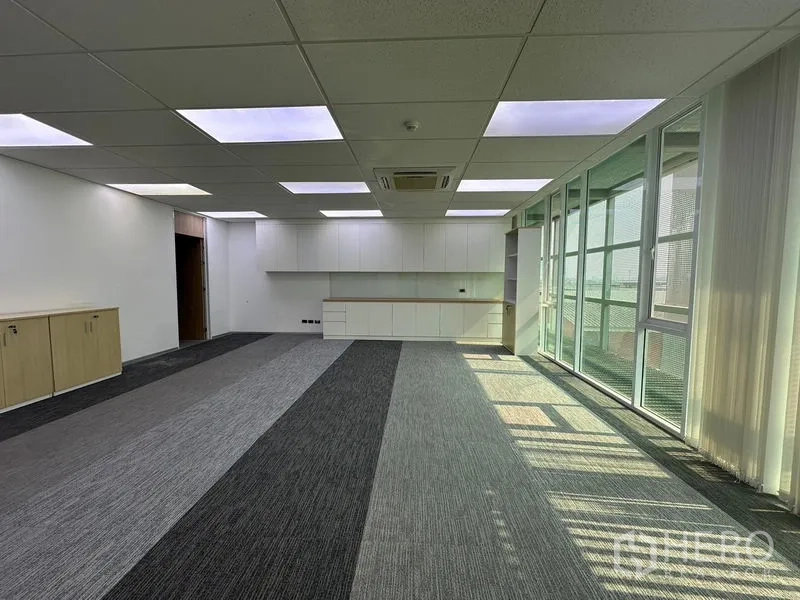 Office Space for rent - Bright multipurpose room with wall cabinets, striped carpet and full-height windows with blinds.