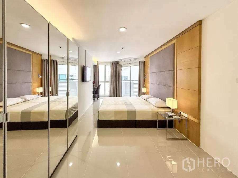 公寓 出租在Khlong Toei, Bangkok - 明亮的主卧，镜面衣柜、软包床头板与落地窗通向阳台。