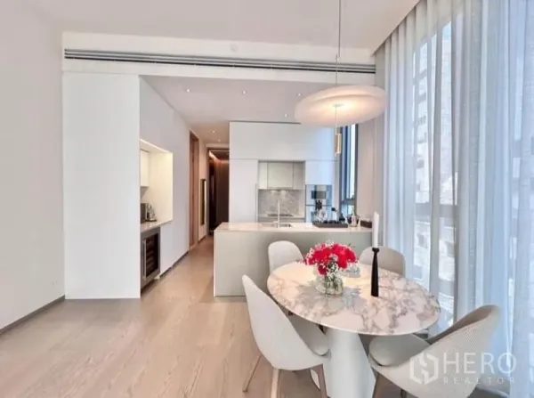 Condominium for rent - Open-plan dining area and modern kitchen with island beside tall sheer windows.