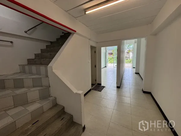 Home Office for rent in Phra Khanong, Bangkok - Tiled hallway with concrete staircase and glass front doors leading outside.